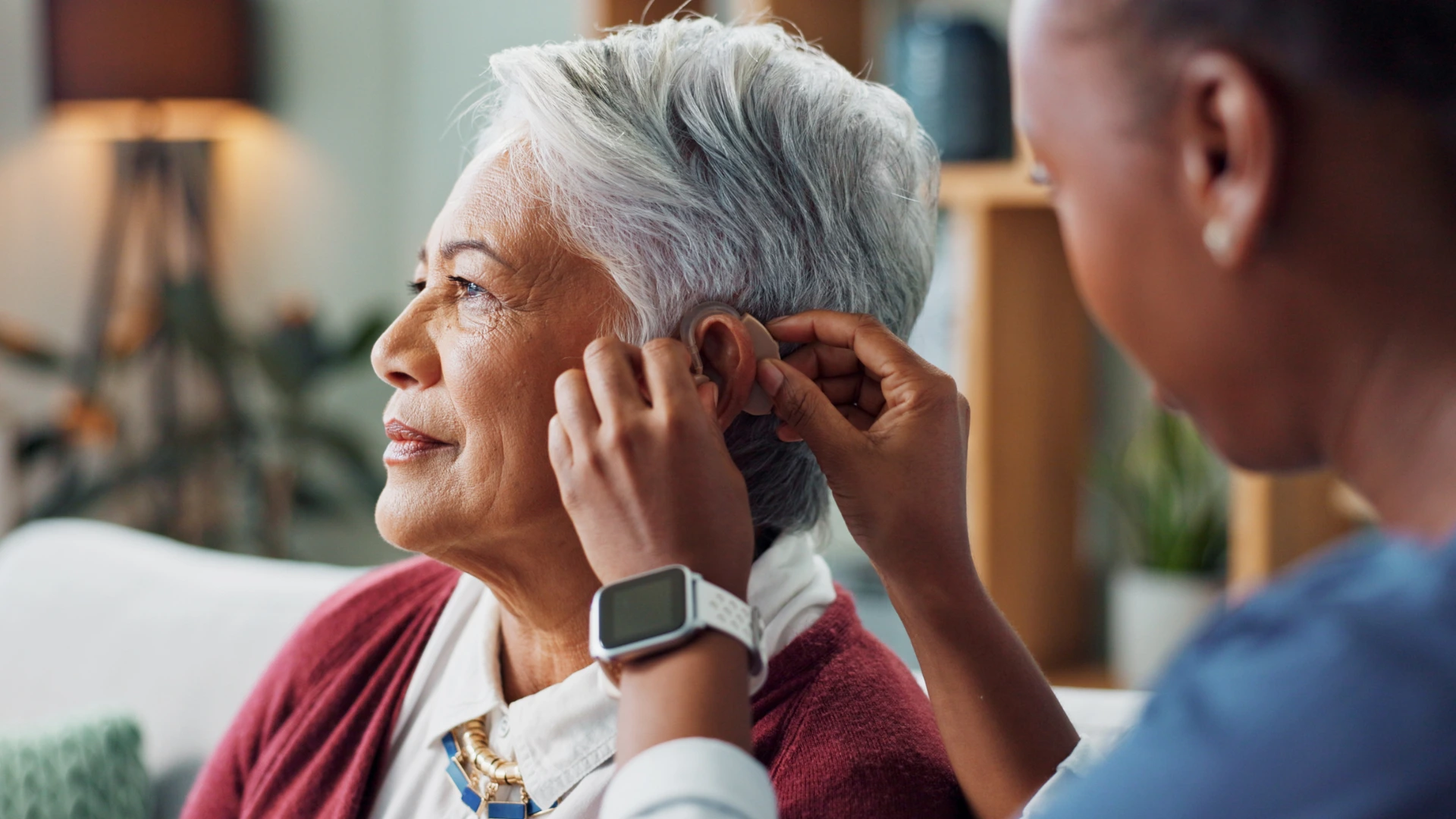 Nurse putting on hearing aid on a patient